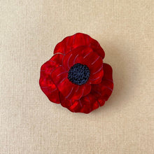 Load image into Gallery viewer, A red and black marbled acrylic poppy flower brooch with a locking pin on the back, displayed on a beige background.
