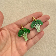 Load image into Gallery viewer, Broccoli-shaped earrings in hand against a beige fabric background.