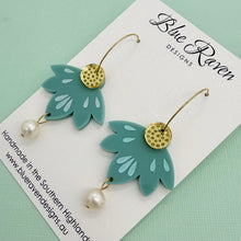 Load image into Gallery viewer, Green leaf-shaped earrings with gold accents and pearl details on a Blue Raven Designs card.
