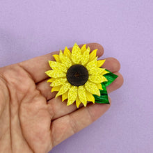Load image into Gallery viewer, Hand holding a yellow sunflower brooch against a purple background
