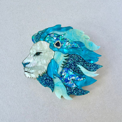 Decorative brooch with a lion design in blue and white on a light gray background