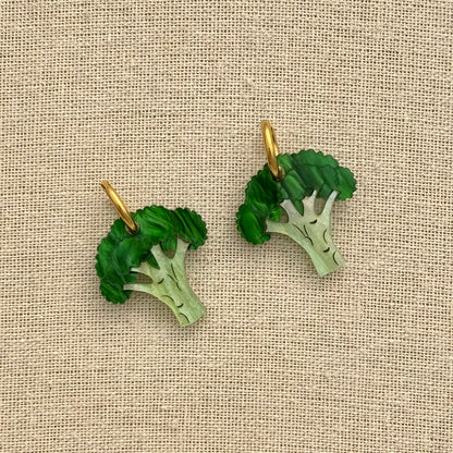 Broccoli-shaped earrings on a beige fabric background