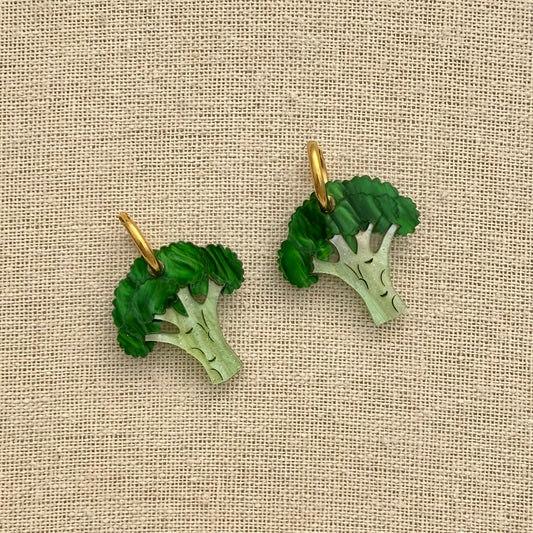 Broccoli-shaped earrings on a beige fabric background