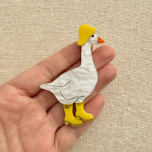 Load image into Gallery viewer, Acrylic goose brooch wearing a yellow hat and boots on a textured beige background
